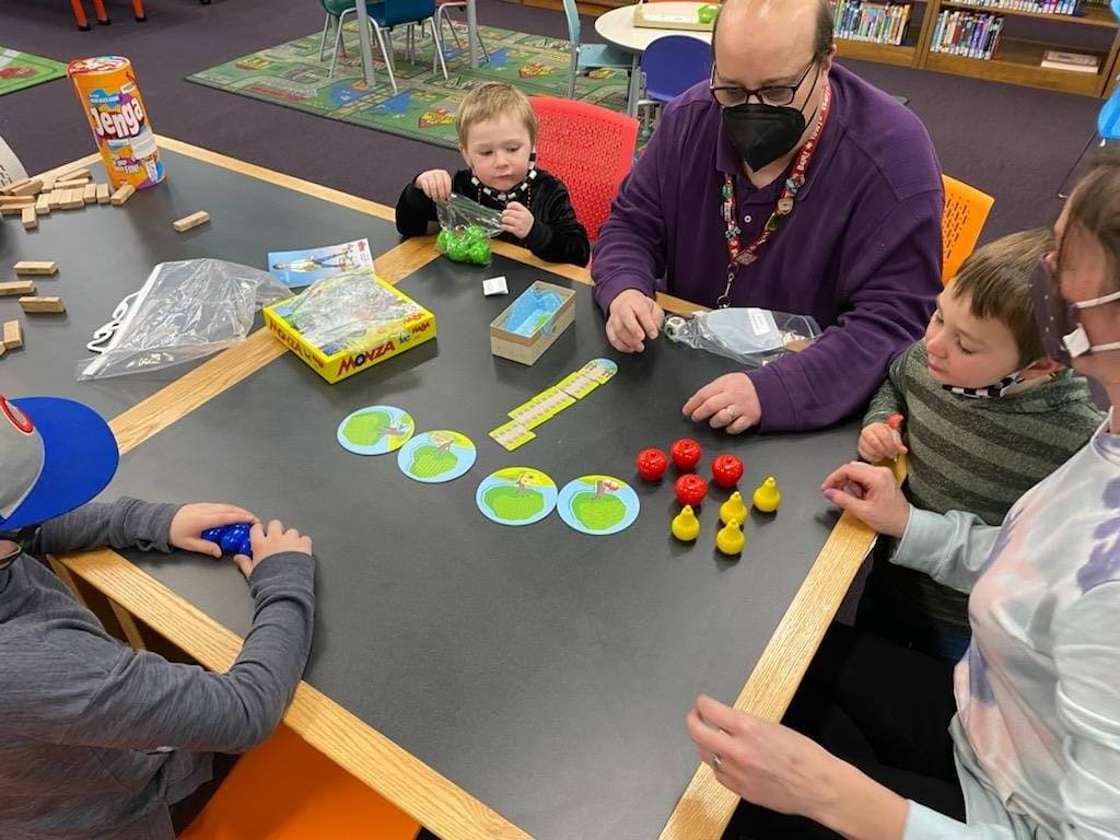 Eltern und Kinder spielen gemeinsam Brettspiele an einem großen Tisch
