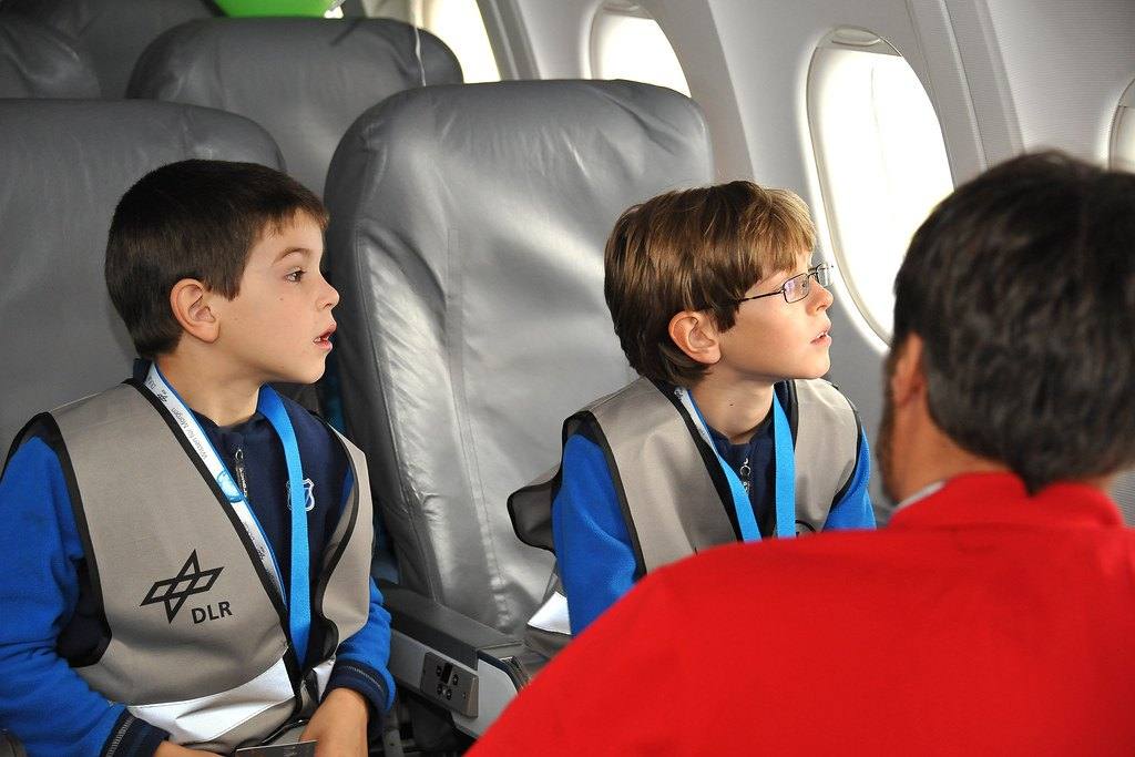 Zwei Kinder sitzen im Flugzeug am Fenster