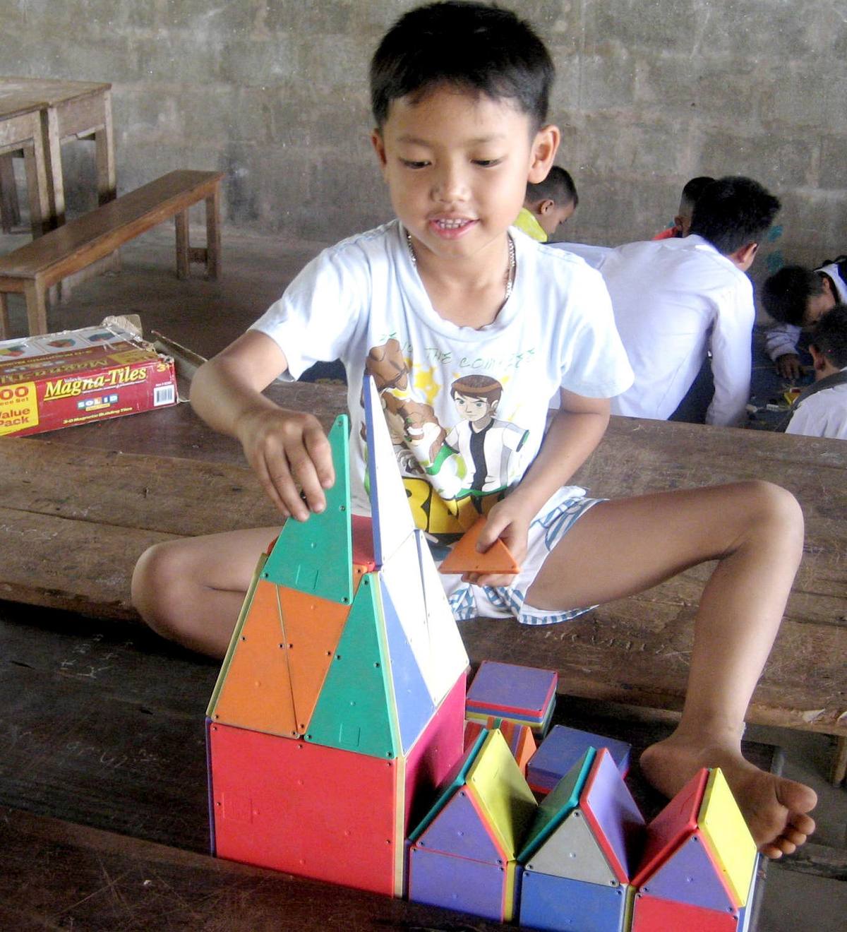 Junge baut mit Magna-Tiles ein buntes Haus
